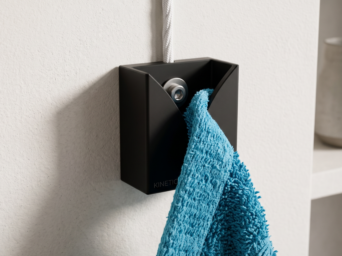 Black wall-mounted towel holder with a blue towel on a light gray wall.